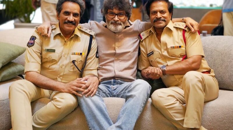 Black and white working still of actor Victory Venkatesh and director Trivikram Srinivas discussing on the sets of the Telugu movie Aadarsha Kutumbam next to a train carriage.